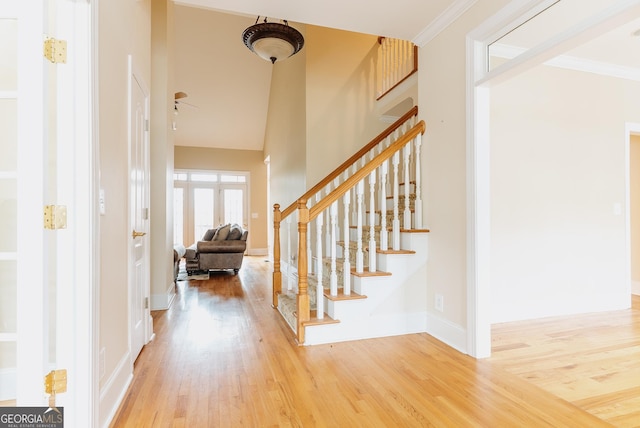 entrance foyer with stairway, baseboards, wood finished floors, and a towering ceiling