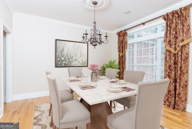 dining room featuring a chandelier, light wood-style flooring, baseboards, and ornamental molding