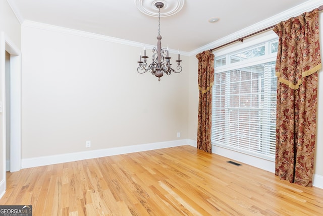 empty room with wood finished floors, baseboards, visible vents, ornamental molding, and a chandelier
