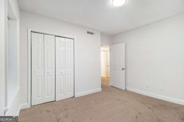 unfurnished bedroom featuring visible vents, baseboards, carpet, and a closet