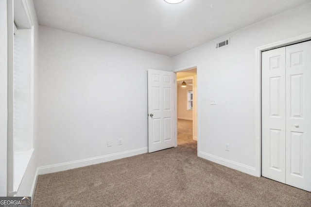 unfurnished bedroom with carpet, visible vents, a closet, and baseboards