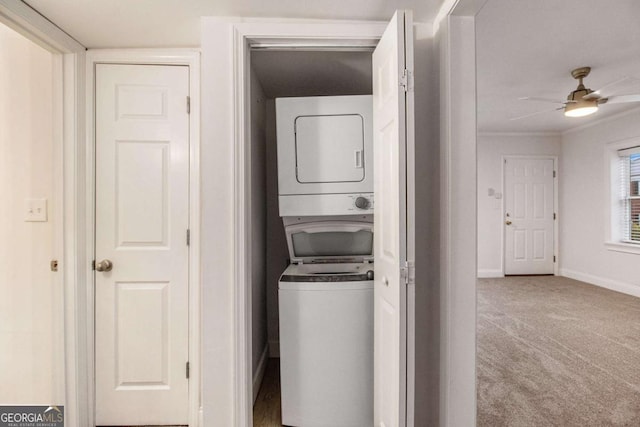 laundry area with a ceiling fan, baseboards, laundry area, stacked washer / dryer, and carpet flooring