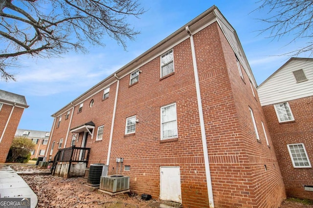 view of side of home featuring central air condition unit and brick siding