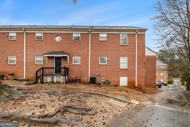 rear view of property featuring central AC unit and brick siding