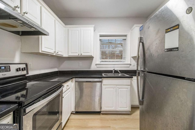 kitchen featuring light wood-type flooring, under cabinet range hood, a sink, stainless steel appliances, and white cabinets