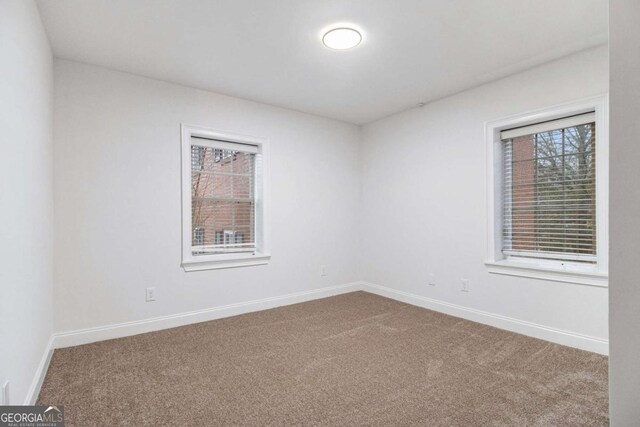 carpeted empty room featuring baseboards