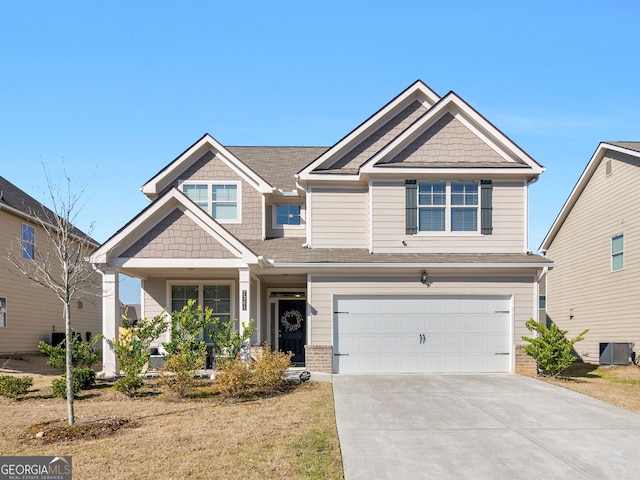 craftsman inspired home featuring a garage, central air condition unit, brick siding, and driveway