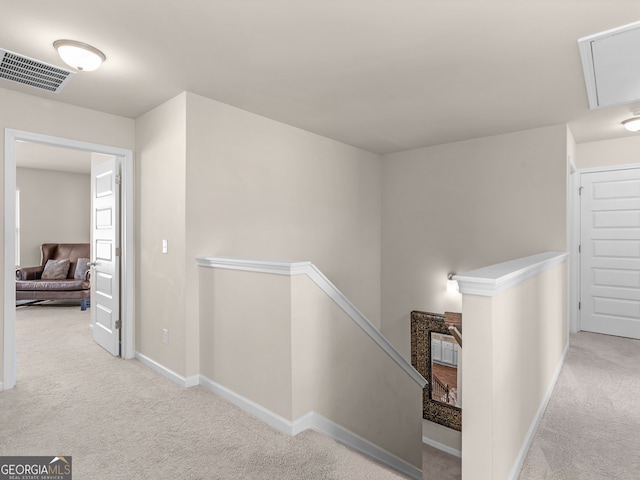 corridor featuring an upstairs landing, visible vents, carpet flooring, and baseboards