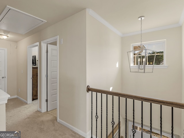 hallway with crown molding, baseboards, light colored carpet, attic access, and an upstairs landing