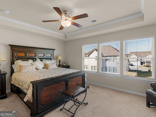 bedroom featuring a tray ceiling, light colored carpet, visible vents, and baseboards