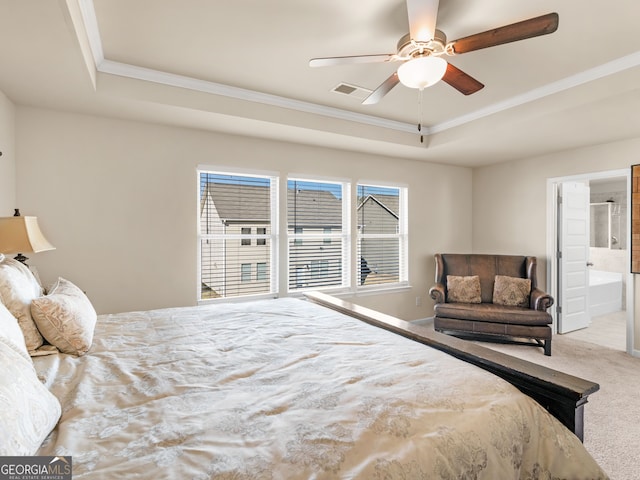 bedroom with visible vents, crown molding, a tray ceiling, carpet flooring, and ensuite bath