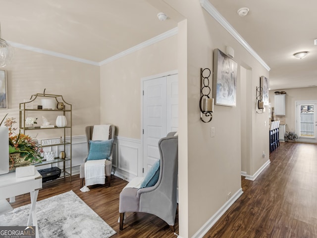 living area featuring wainscoting, baseboards, wood finished floors, and crown molding