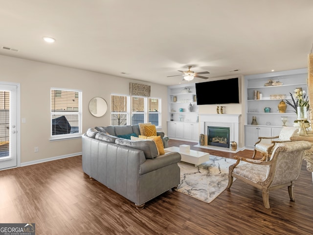 living area featuring ceiling fan, visible vents, a healthy amount of sunlight, and wood finished floors