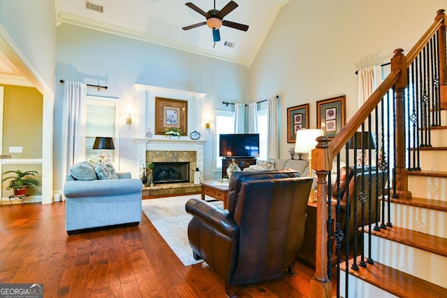 living room featuring visible vents, dark wood-type flooring, high vaulted ceiling, a stone fireplace, and ceiling fan