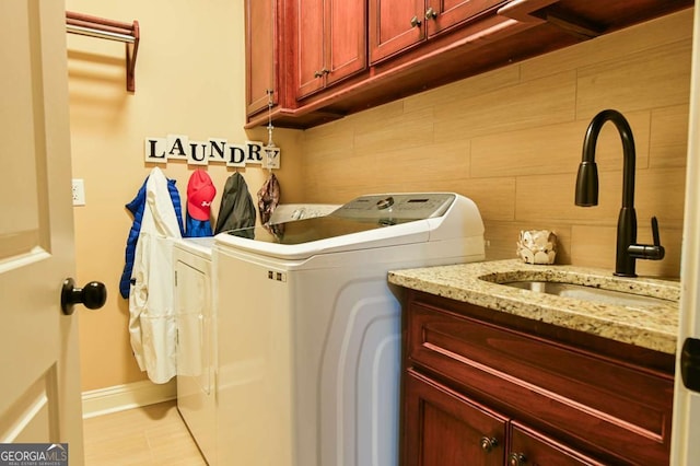 laundry area featuring washer and dryer, cabinet space, and a sink