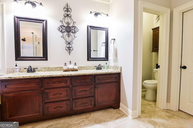 bathroom with a sink, baseboards, toilet, and double vanity