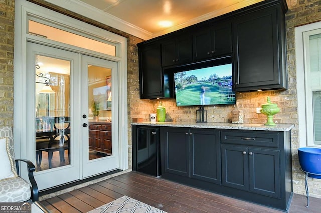 bar with dark wood-type flooring, refrigerator, french doors, brick wall, and crown molding