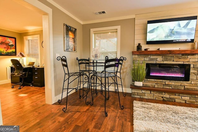 dining space featuring visible vents, baseboards, wood finished floors, and crown molding