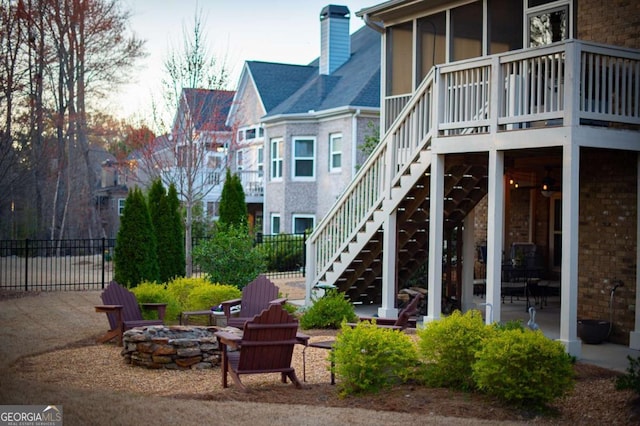 rear view of house featuring a patio, stairs, an outdoor fire pit, fence, and a chimney