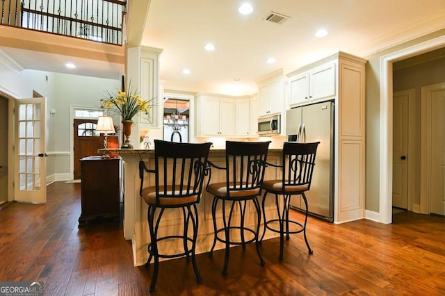 kitchen featuring visible vents, appliances with stainless steel finishes, dark wood-style floors, and crown molding