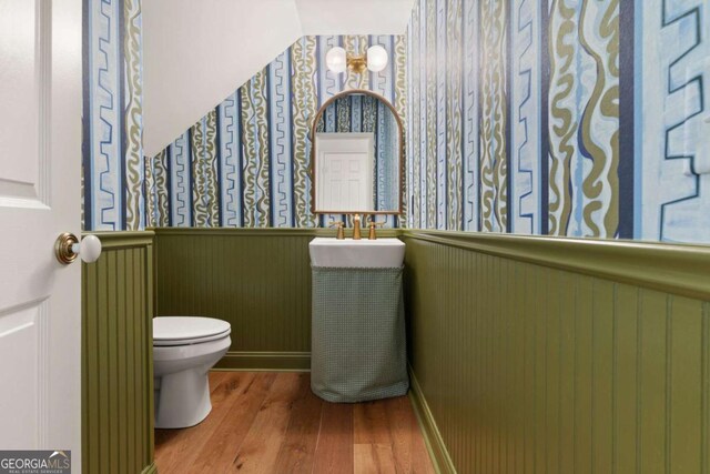bathroom featuring radiator, toilet, wood finished floors, and wainscoting