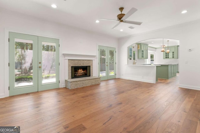 unfurnished living room with arched walkways, recessed lighting, french doors, and hardwood / wood-style flooring