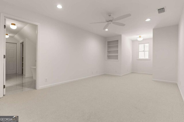 unfurnished room featuring visible vents, built in features, recessed lighting, light colored carpet, and ceiling fan