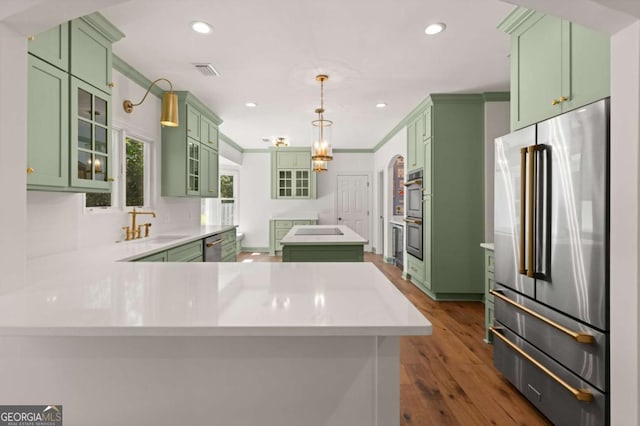 kitchen with visible vents, a center island, green cabinetry, stainless steel appliances, and a sink
