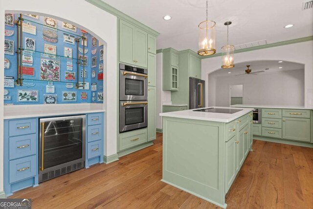 kitchen with green cabinets, ceiling fan, wine cooler, appliances with stainless steel finishes, and arched walkways