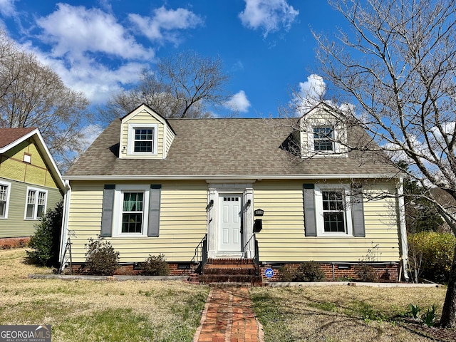 cape cod house with a front lawn, roof with shingles, and crawl space