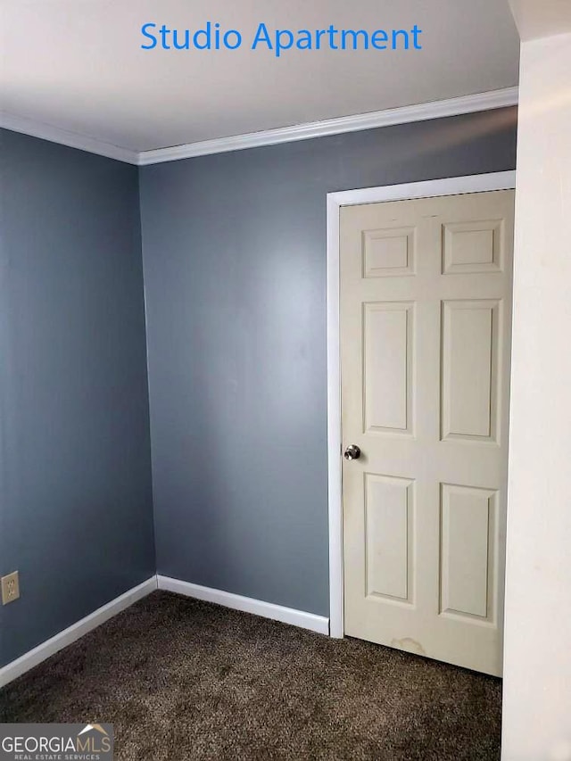 unfurnished room featuring crown molding, baseboards, and dark colored carpet