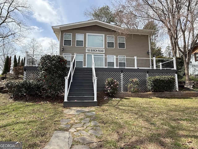 rear view of property featuring a deck, stairs, and a yard