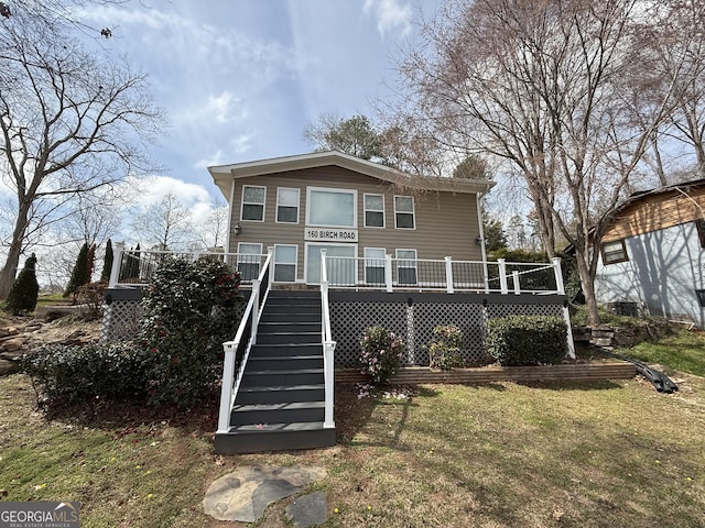 back of property featuring a wooden deck, a lawn, and stairs