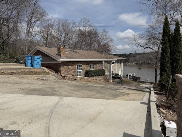 view of front of home with concrete driveway, a chimney, and roof with shingles