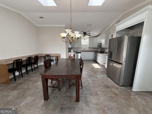 dining space featuring an inviting chandelier, vaulted ceiling with skylight, crown molding, and visible vents