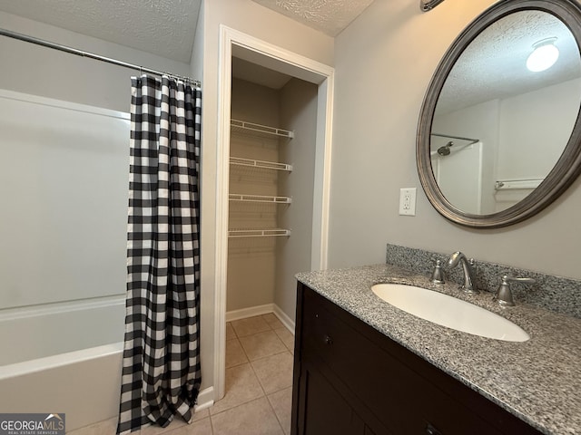 full bathroom with tile patterned flooring, vanity, and a textured ceiling