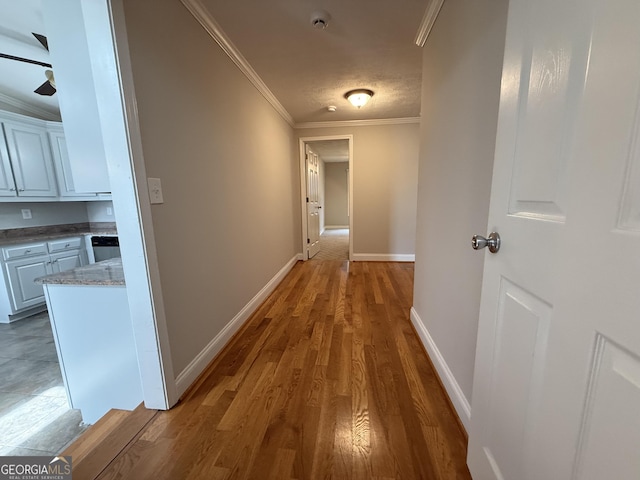 corridor with crown molding, baseboards, and wood finished floors