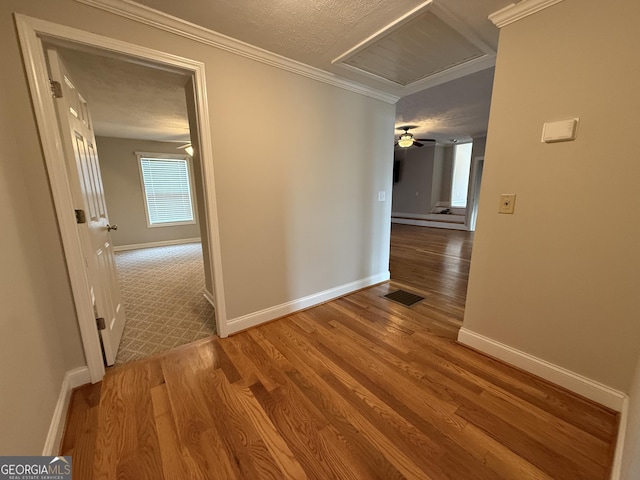 hallway featuring visible vents, a textured ceiling, baseboards, and wood finished floors