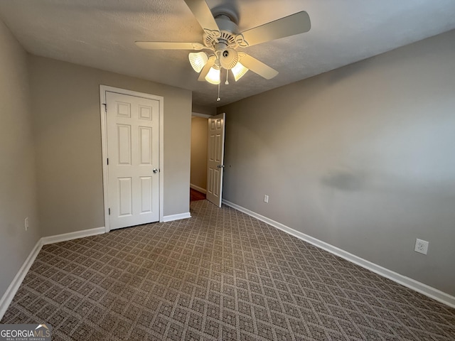 unfurnished bedroom featuring baseboards, a textured ceiling, ceiling fan, and dark carpet