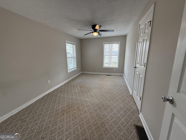 carpeted empty room with visible vents, baseboards, a textured ceiling, and ceiling fan