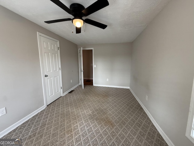 unfurnished bedroom featuring baseboards, carpet floors, a textured ceiling, and a ceiling fan