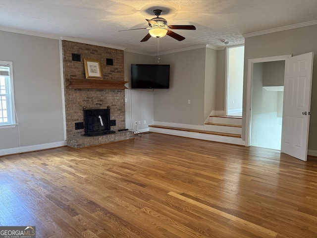 unfurnished living room with crown molding, wood finished floors, baseboards, and ceiling fan