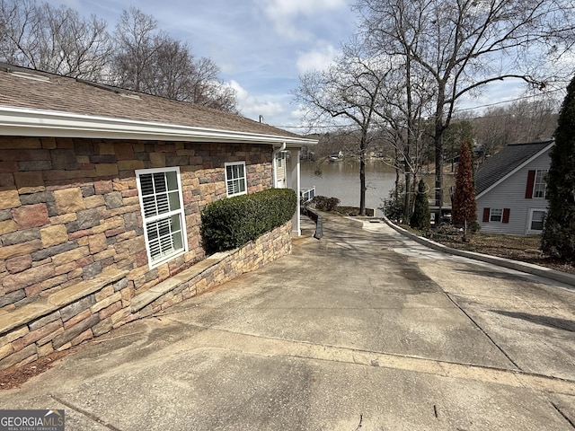 view of property exterior featuring stone siding and roof with shingles