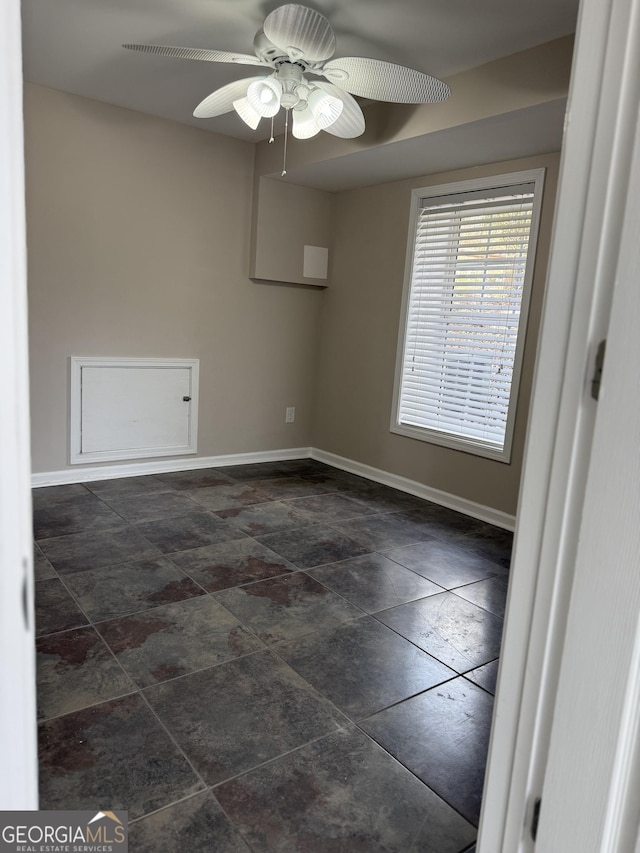 unfurnished room featuring a ceiling fan and baseboards