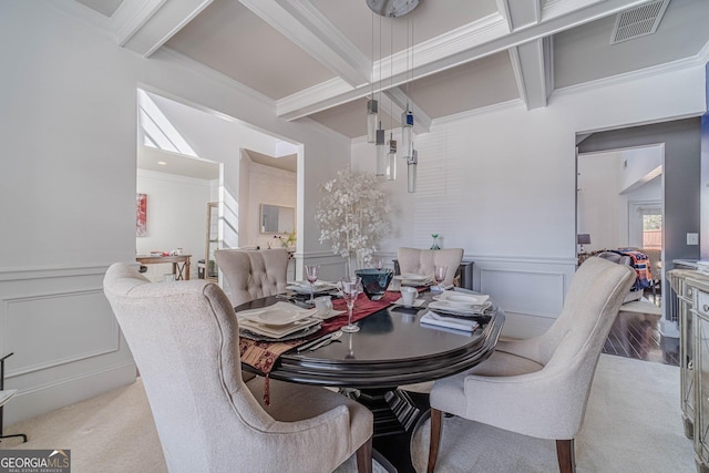 dining area featuring beam ceiling, a decorative wall, visible vents, and ornamental molding