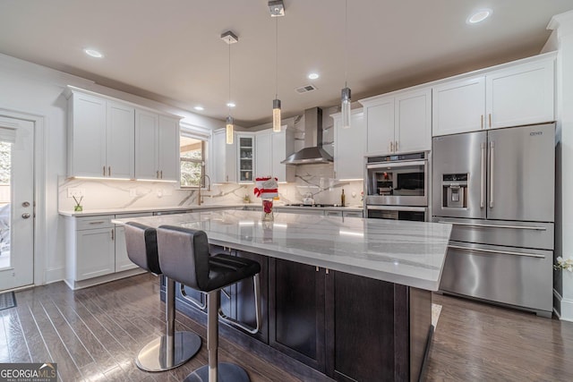 kitchen featuring a center island, dark wood-style floors, stainless steel appliances, and wall chimney range hood