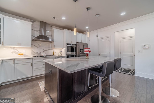 kitchen featuring visible vents, a center island, white cabinetry, appliances with stainless steel finishes, and wall chimney exhaust hood