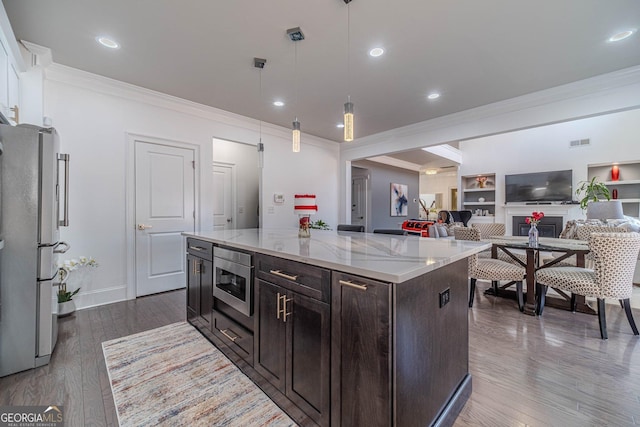 kitchen featuring visible vents, dark wood finished floors, hanging light fixtures, appliances with stainless steel finishes, and crown molding