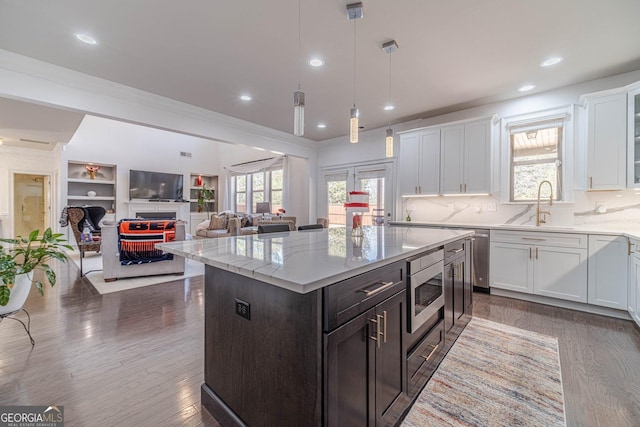 kitchen with stainless steel microwave, a healthy amount of sunlight, white cabinetry, and a sink