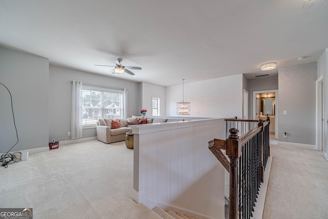 living area featuring light colored carpet, baseboards, and a ceiling fan